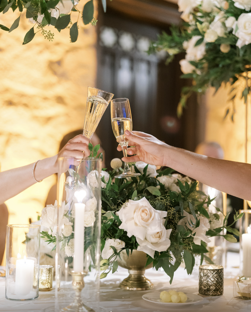 bride and groom making toast in front of white rose floral arrangement